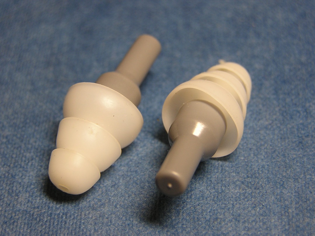 A pair of reusable triple-flange musician's earplugs with attenuating filters, the low-profile design used to cut stage volume without dulling pitch or timbre