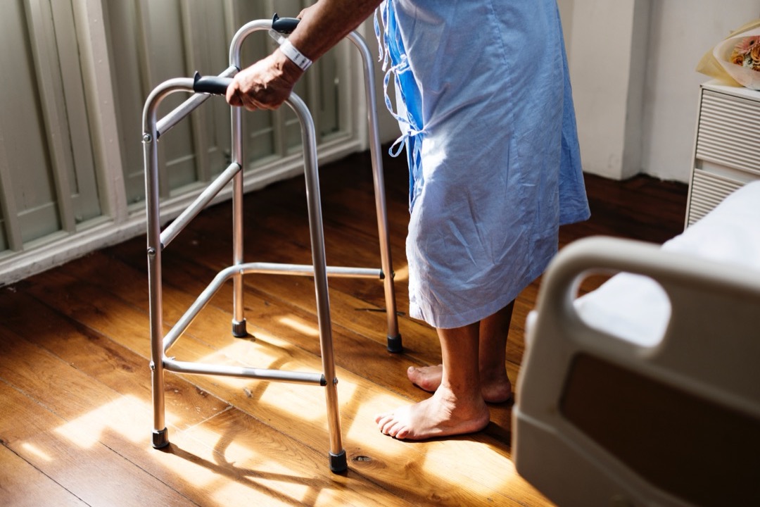 A raised toilet seat with grab bars installed in a home bathroom — one of the highest-leverage modifications for safe post-surgery recovery