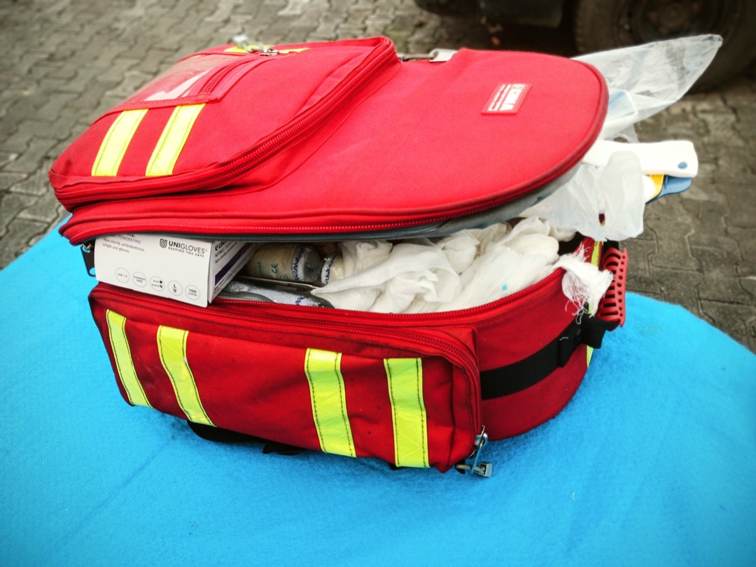 An open home first aid kit laid out with bandages, gauze, medical tape, gloves, and instruments organized in compartments