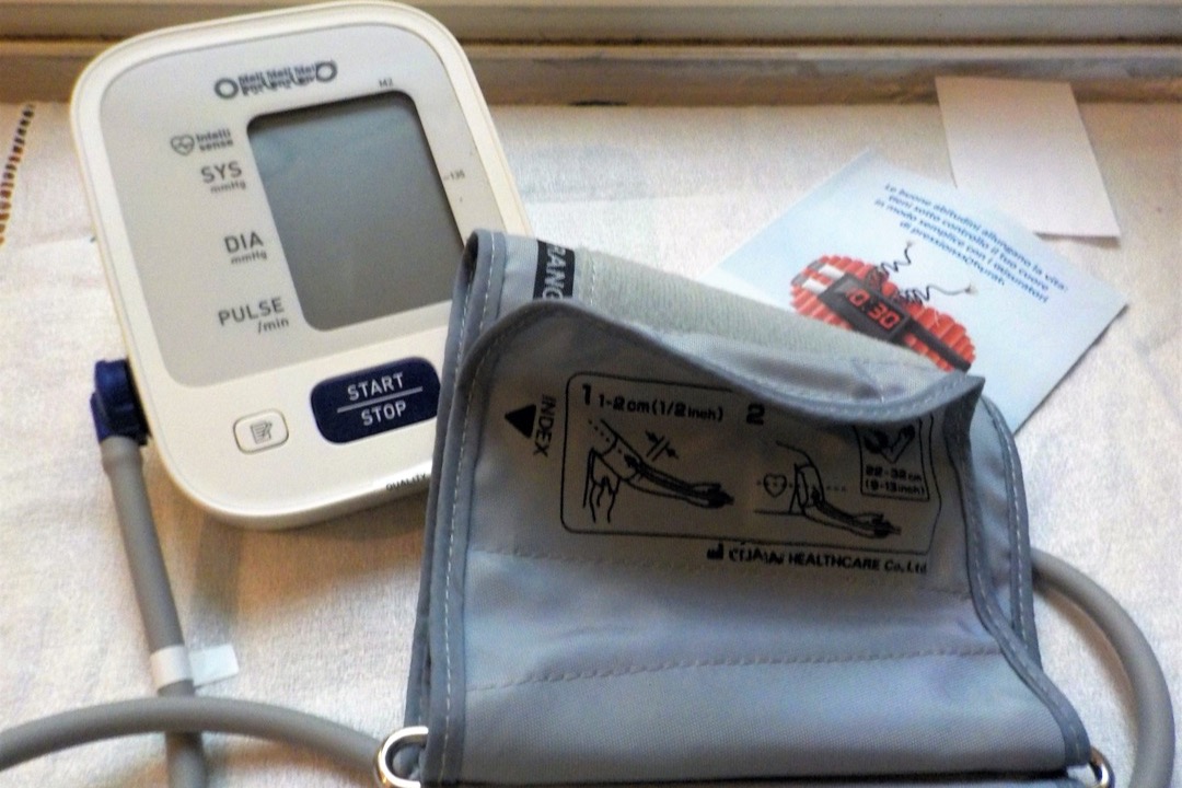 Validated upper-arm blood pressure cuff positioned correctly on a bare bicep with an automatic oscillometric monitor displaying a reading