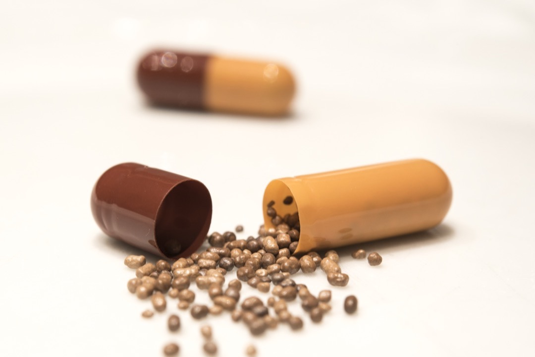 Opened iron supplement capsule with slow-release iron beads spilling out